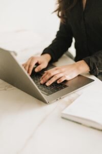 Hands typing on a laptop in a warm, minimalist workspace, visually representing a virtual assistant workflow in action.