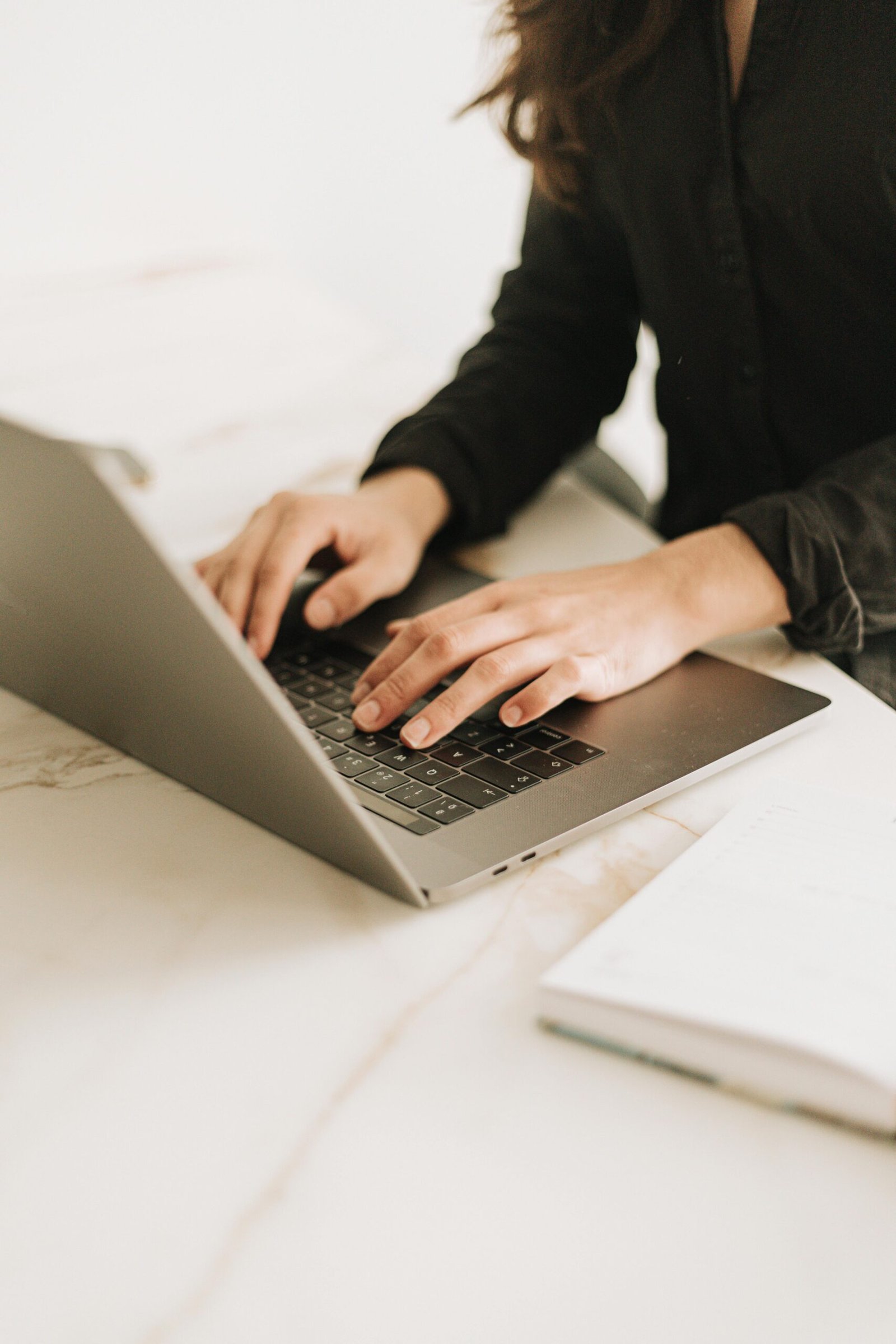 Hands typing on a laptop in a warm, minimalist workspace, visually representing a virtual assistant workflow in action.
